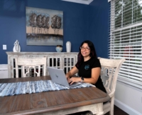 Marina seated at table smiling and typing on HP laptop.